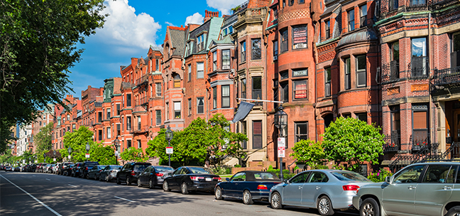 Image of Commonwealth Avenue with brownstone row houses and parked cars in the Back Bay area of downtown Boston